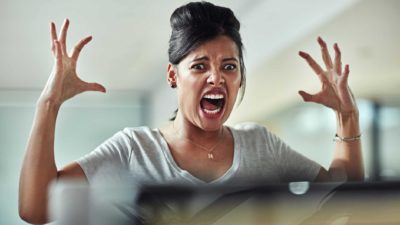 A woman screams and holds her hands up in frustration.