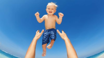 hands throwing smiling baby up in the air representing rising asx share price