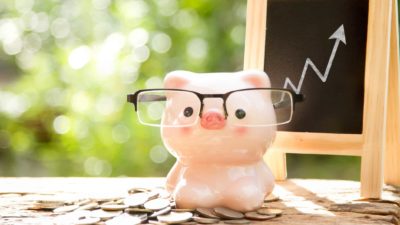 Piggy bank in front of blackboard chart with rising arrow