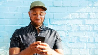 man looks at phone while disappointed