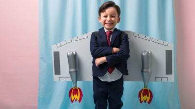 Boy in business suit smiles with arms crossed and rockets attached to his back representing the rocketing BrainChip share price