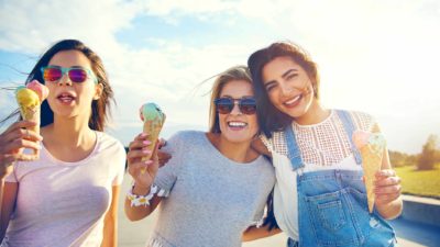 Three women cruise along enjoying ice-creams in the sunshine.